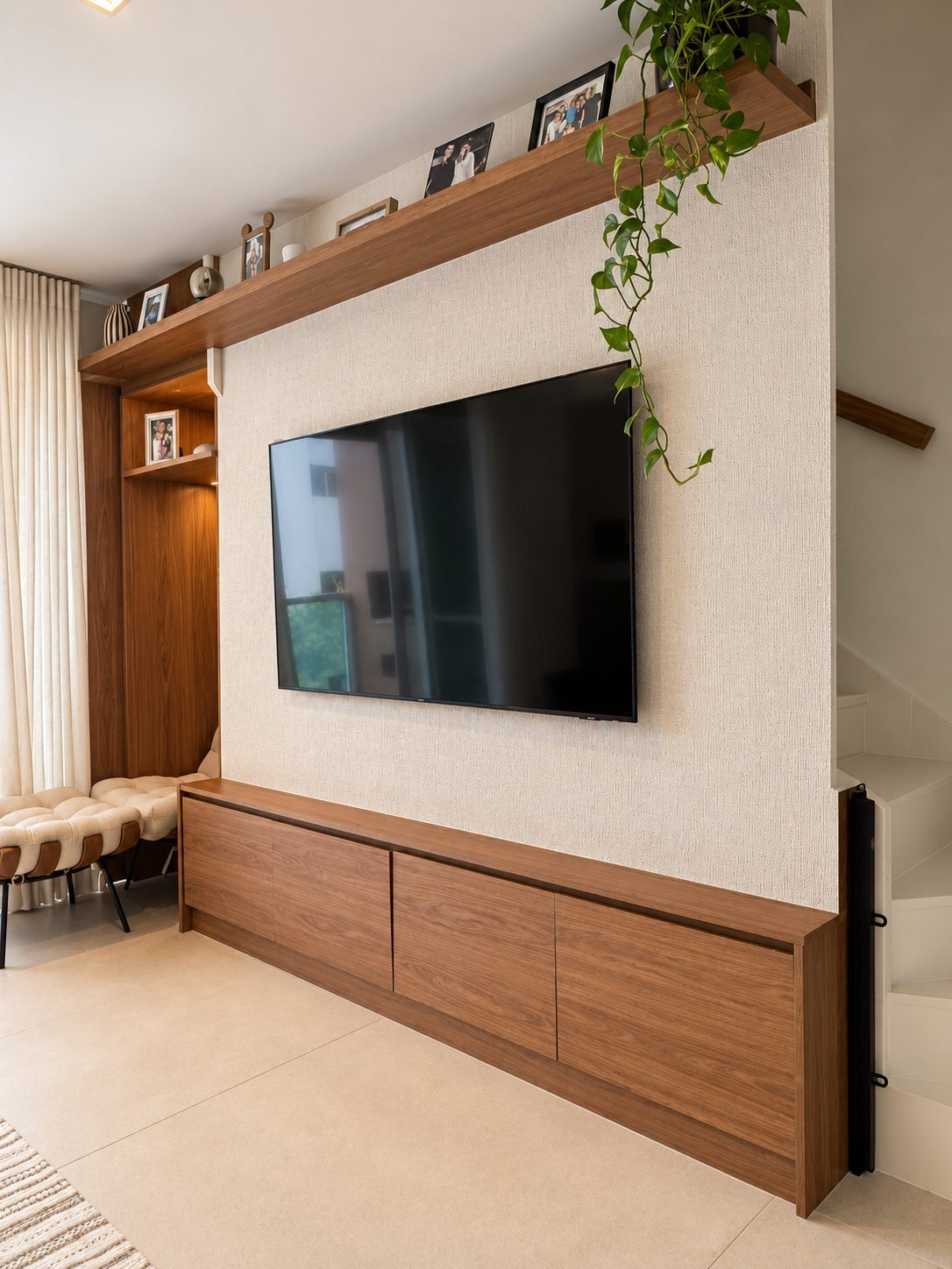 Sala de estar em pé-direito duplo, com painel de TV em linho claro, marcenaria em madeira e mezanino com guarda-corpo de vidro